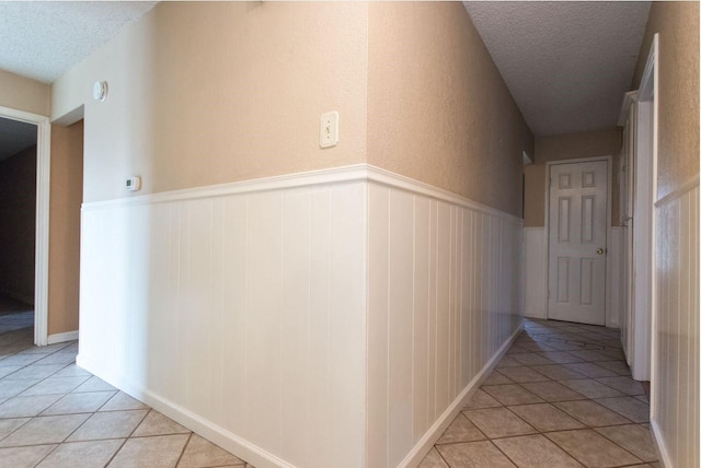 hall featuring light tile patterned floors and a textured ceiling