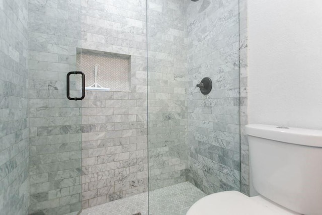 bathroom featuring toilet and a shower with shower door