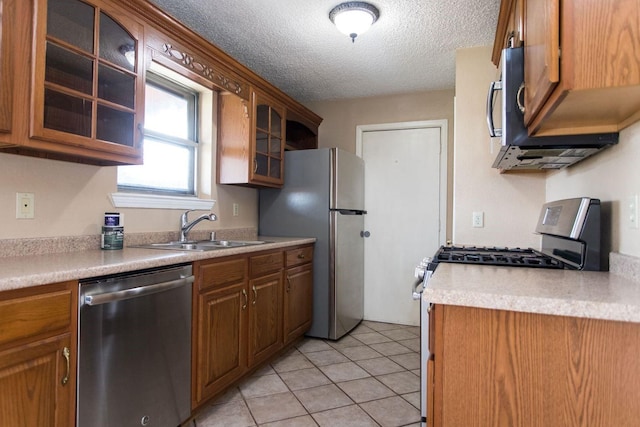 kitchen featuring sink, stainless steel appliances, a textured ceiling, and light tile patterned flooring