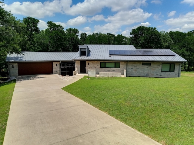 1621 Caddys Cir, Garland, TX 75043 - view of front of property with stone siding, a standing seam roof, an attached garage, concrete driveway, and roof mounted solar panels