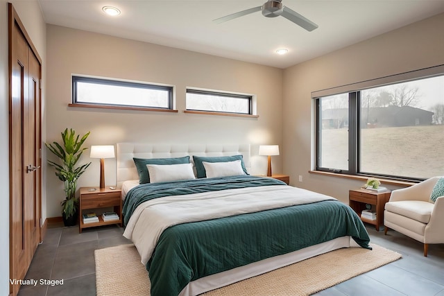 bedroom featuring ceiling fan, dark tile patterned flooring, and multiple windows