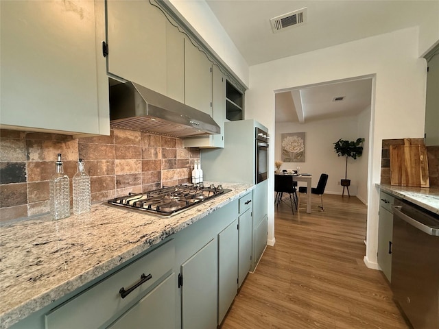 kitchen featuring visible vents, range hood, stainless steel appliances, light wood-type flooring, and backsplash