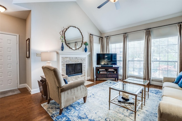 living room featuring dark wood-type flooring, ceiling fan, a stone fireplace, and high vaulted ceiling