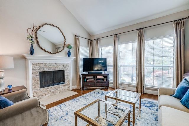 living room with lofted ceiling, a stone fireplace, and wood-type flooring