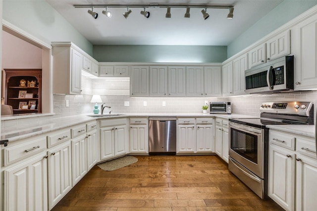 kitchen with white cabinetry, sink, backsplash, light hardwood / wood-style floors, and stainless steel appliances