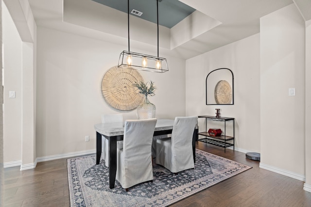 dining space featuring dark hardwood / wood-style flooring and a raised ceiling