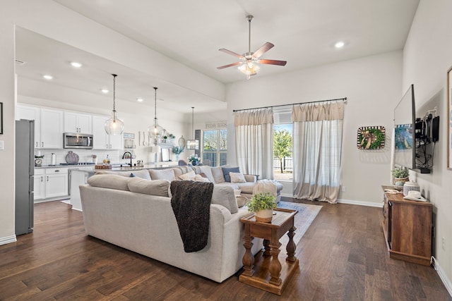 living room featuring dark wood-type flooring, ceiling fan, and sink