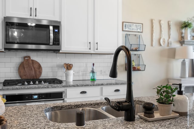 kitchen featuring appliances with stainless steel finishes, light stone countertops, and white cabinets