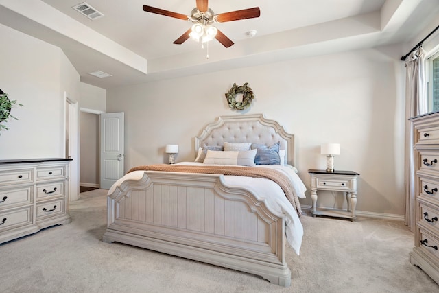 bedroom featuring light colored carpet, a raised ceiling, and ceiling fan