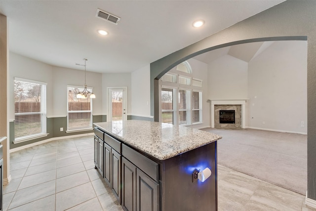 200 Ravenel St, Glenn Heights, TX 75154 - kitchen featuring arched walkways, light stone countertops, a kitchen island, light tile patterned floors, and a high end fireplace