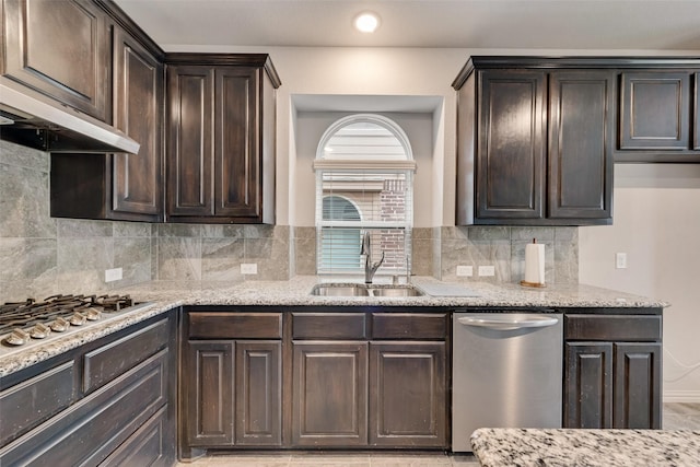 kitchen with sink, light stone counters, dark brown cabinets, appliances with stainless steel finishes, and backsplash