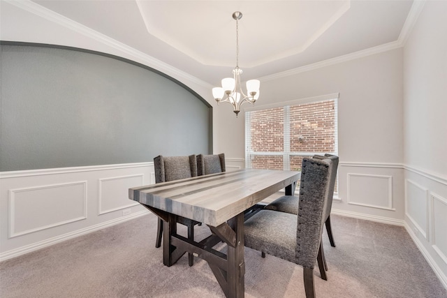 dining room with a raised ceiling, crown molding, light carpet, and an inviting chandelier