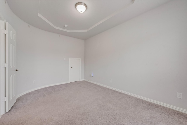 carpeted spare room featuring a tray ceiling