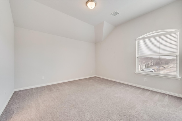 carpeted empty room featuring lofted ceiling