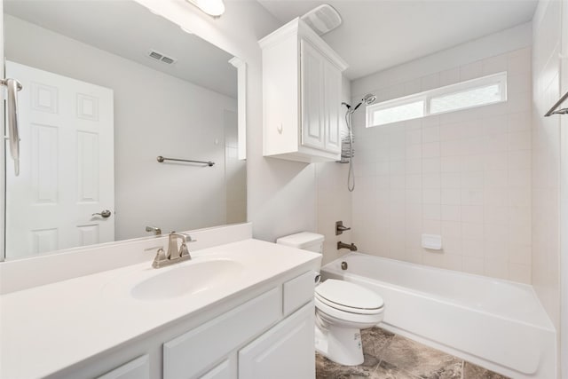 full bathroom with tiled shower / bath, vanity, and toilet