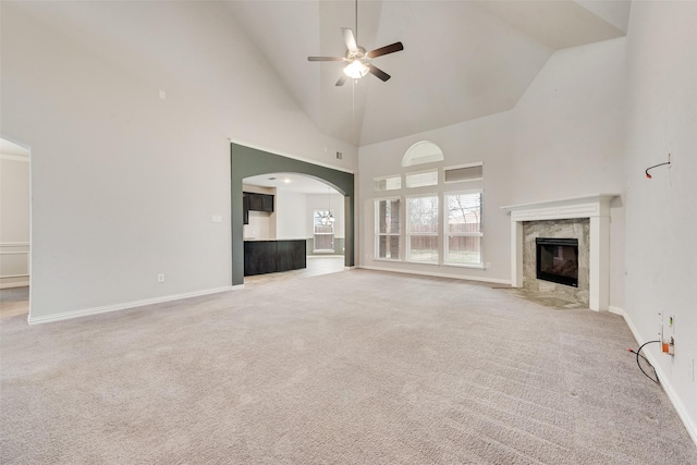 unfurnished living room with ceiling fan, high vaulted ceiling, a fireplace, and light colored carpet