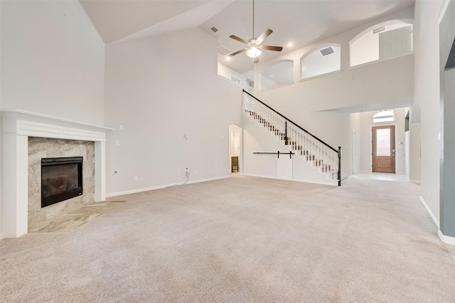 unfurnished living room with ceiling fan, light colored carpet, a fireplace, and high vaulted ceiling