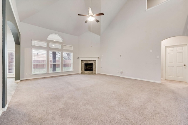 unfurnished living room with ceiling fan, a premium fireplace, high vaulted ceiling, and light carpet