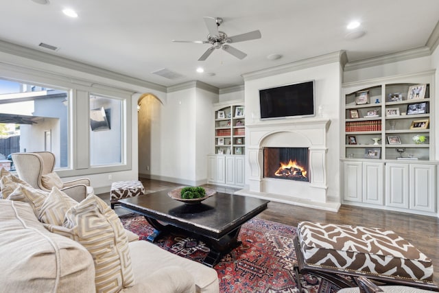 living room with built in shelves, ceiling fan, ornamental molding, and dark hardwood / wood-style floors