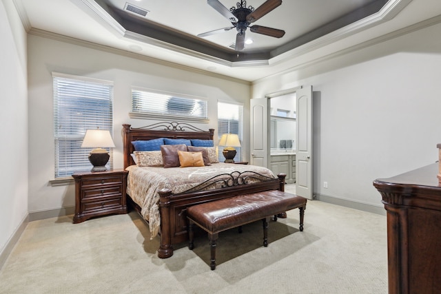 carpeted bedroom with crown molding, ceiling fan, ensuite bathroom, and a raised ceiling