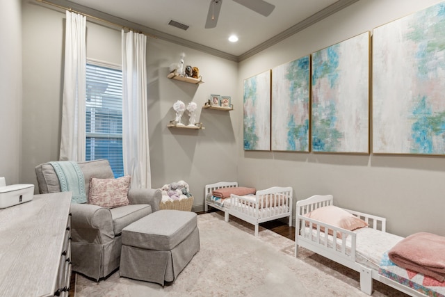 bedroom featuring a crib, crown molding, wood-type flooring, and ceiling fan