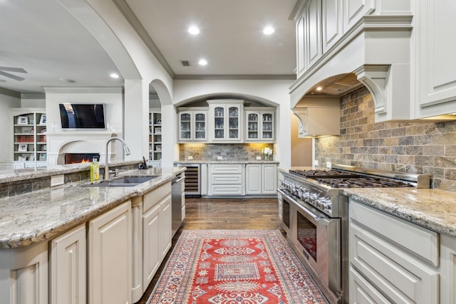 kitchen featuring appliances with stainless steel finishes, sink, white cabinets, ornamental molding, and light stone countertops