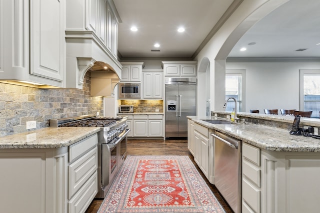 kitchen featuring white cabinetry, a kitchen island with sink, and built in appliances