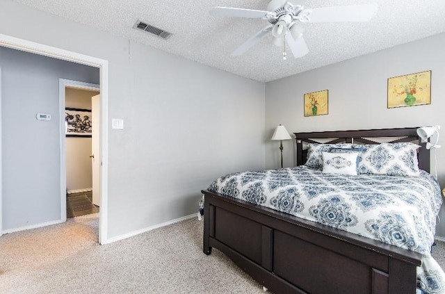 bedroom featuring light carpet, ceiling fan, and a textured ceiling