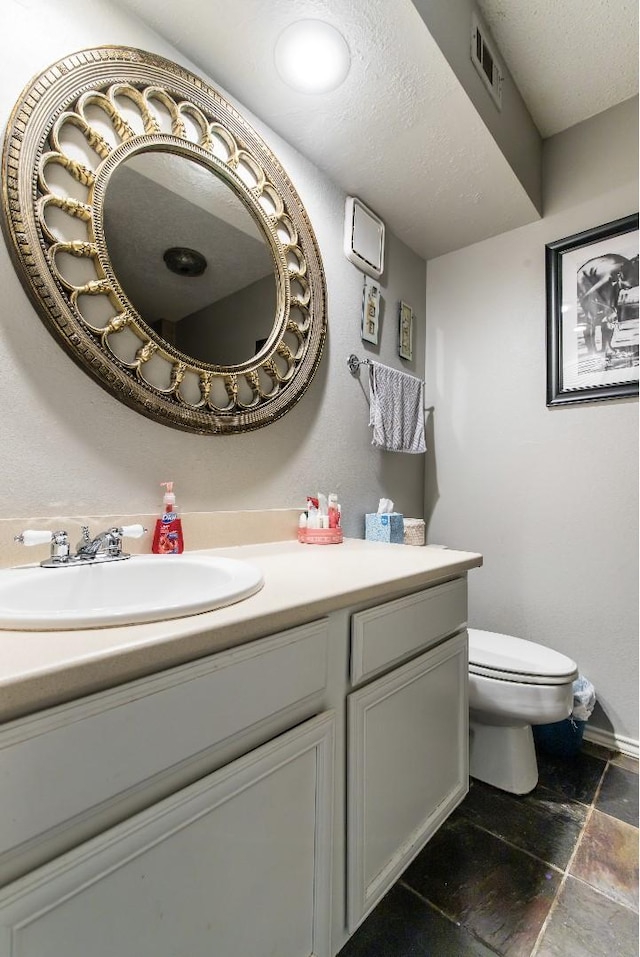 bathroom with vanity, toilet, and a textured ceiling