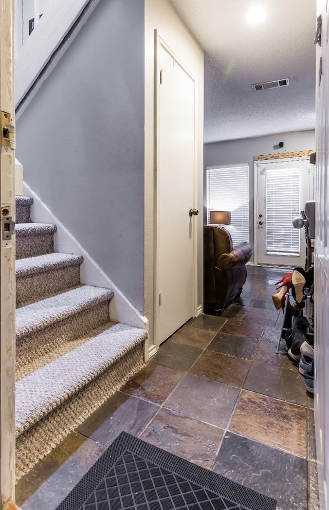 stairs with a textured ceiling