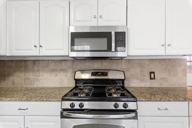 kitchen with dark stone countertops, stainless steel appliances, and white cabinets