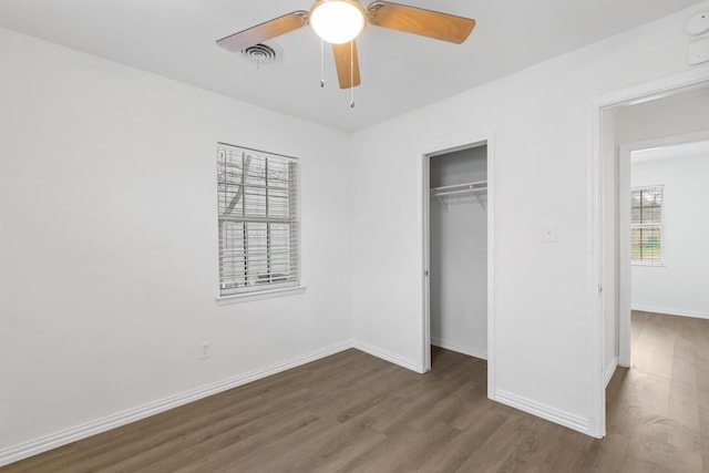 unfurnished bedroom featuring dark hardwood / wood-style floors, ceiling fan, and a closet