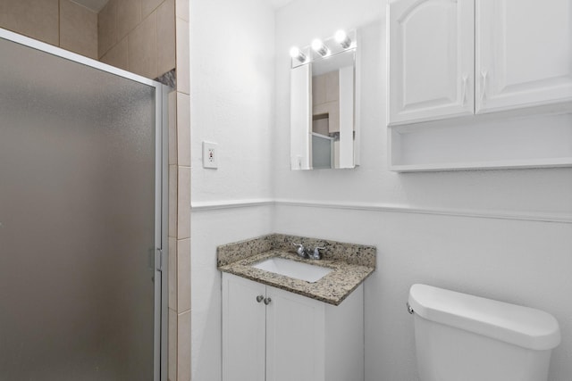 bathroom with walk in shower, vanity, and toilet