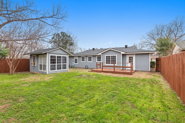 rear view of property with a lawn, a sunroom, and a deck