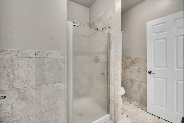 bathroom featuring tile walls, toilet, and walk in shower