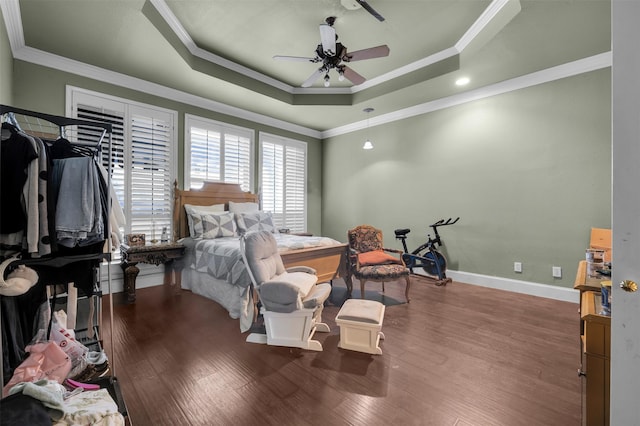 bedroom with crown molding, ceiling fan, wood-type flooring, and a tray ceiling