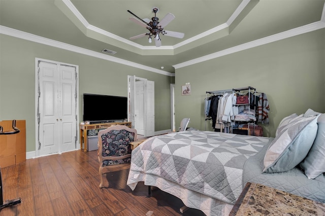 bedroom with crown molding, hardwood / wood-style floors, and a tray ceiling