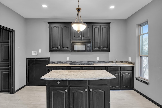 kitchen with sink, light hardwood / wood-style flooring, hanging light fixtures, a center island, and black appliances