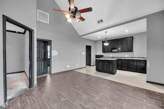 kitchen with pendant lighting, sink, ceiling fan, high vaulted ceiling, and a kitchen island