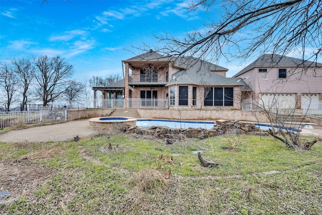 back of property with an in ground hot tub and a balcony