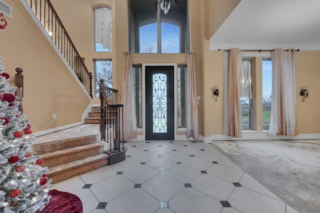 entryway featuring crown molding, a towering ceiling, and a healthy amount of sunlight