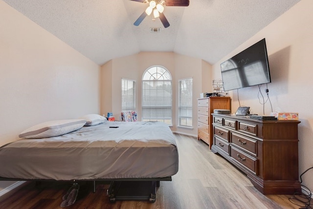 bedroom featuring ceiling fan, vaulted ceiling, light hardwood / wood-style floors, and a textured ceiling