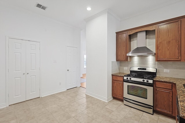 kitchen with tasteful backsplash, gas range, wall chimney range hood, and dark stone counters