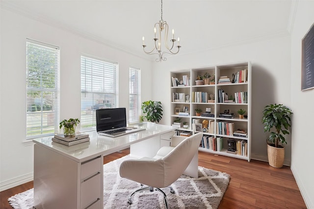 office area with dark wood-type flooring, ornamental molding, and an inviting chandelier