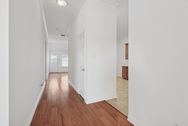 hallway with ornamental molding and light wood-type flooring