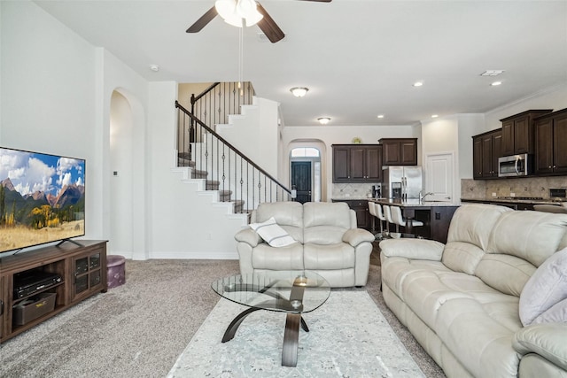 carpeted living room featuring ceiling fan and sink