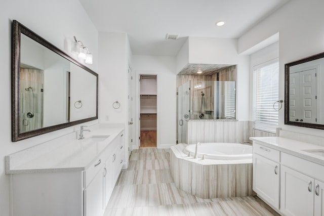 bathroom with vanity and shower with separate bathtub