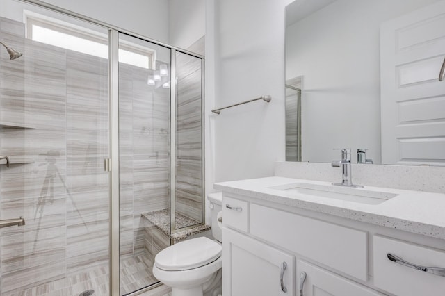 bathroom featuring an enclosed shower, vanity, and toilet