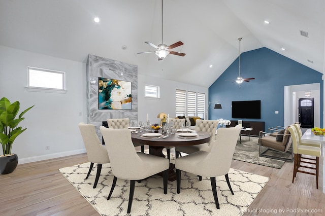 dining space featuring high vaulted ceiling, light hardwood / wood-style floors, and a healthy amount of sunlight