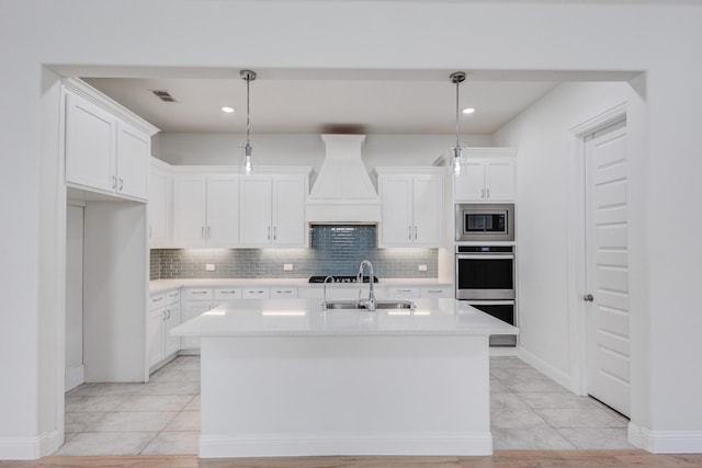 kitchen with sink, appliances with stainless steel finishes, hanging light fixtures, an island with sink, and white cabinets